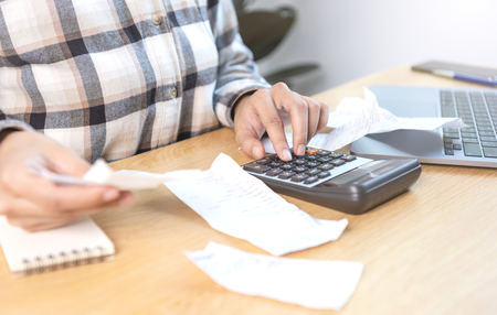 Left or right mulher de negocios pressionando a calculadora calcula os varios custos que devem ser pagos pelas notas fiscais retidas e colocadas na mesa